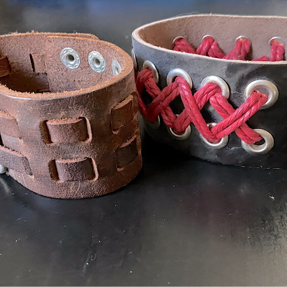 LOT of two leather wrist cuffs. Brown leather with silver metal detail.